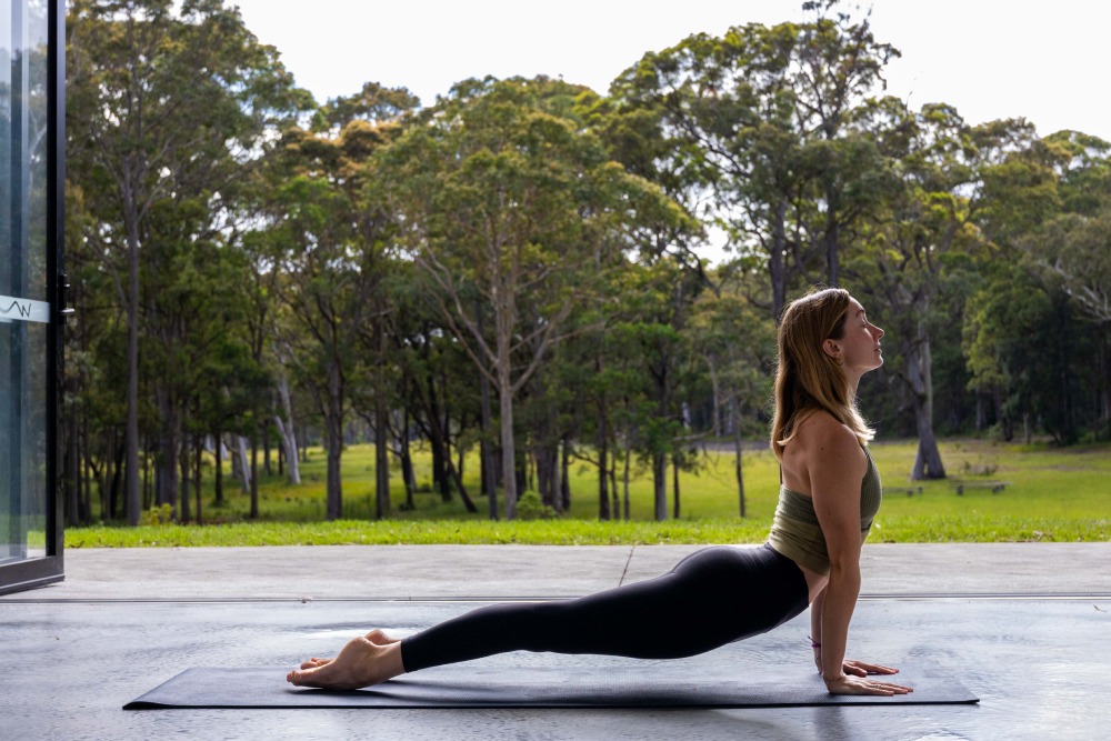 Woman practicing yoga at Melaleuca Worrowing Jervis Bay with bushland views