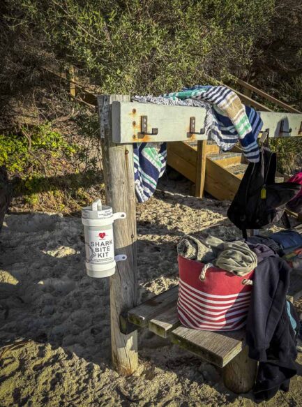 A wooden bench at the south end of Huskisson Beach with a Shark Bite Kit cylinder attached.