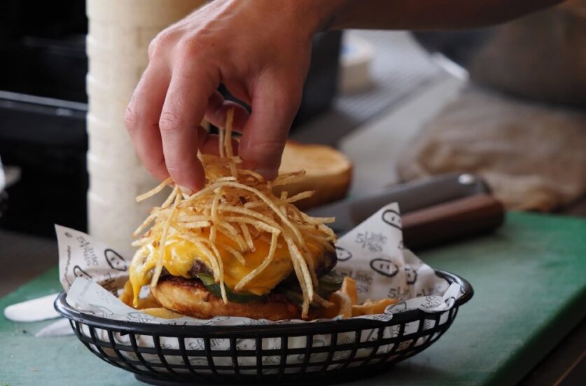 A chef adds a garnish to the cheeseburger at the 5 Little Pigs food truck in Woollamia, Jervis Bay.
