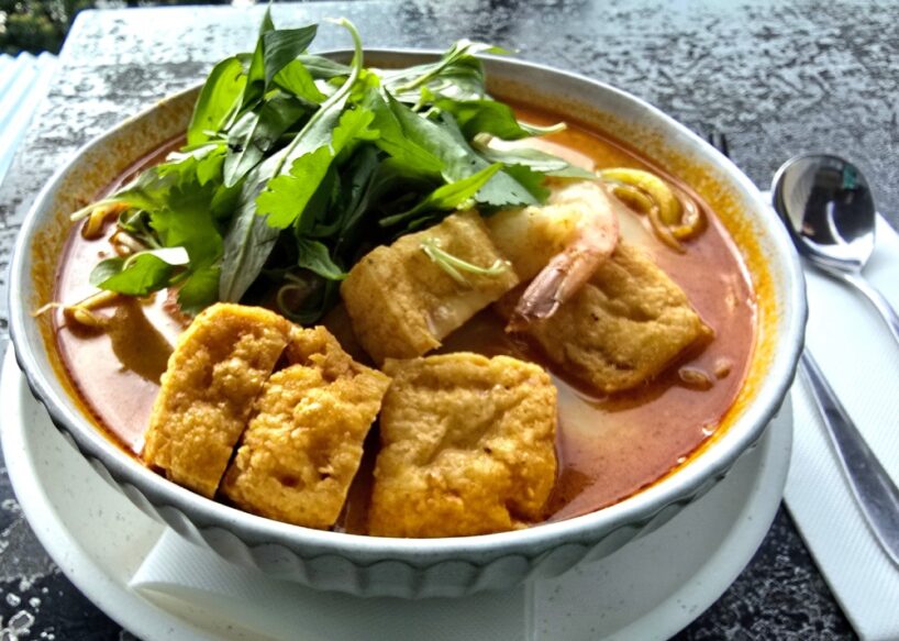 Close-up on a bowl of laksa at the Huskisson Hotel with added Queensland prawns and topped with Asian herbs.
